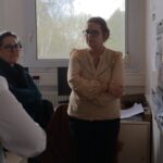 trois femmes face à des affiches collées au mur